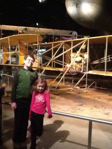 a boy and girl standing in front of an airplane