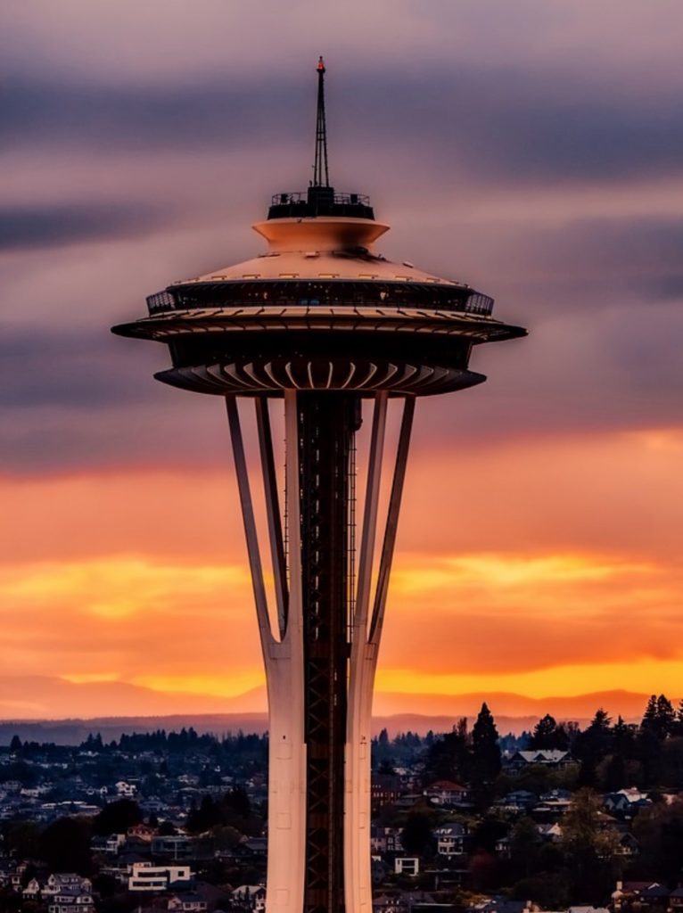 a tall tower with a dome with Space Needle in the background
