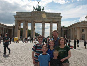 a group of people posing for a photo in front of a stone structure with Brandenburg Gate in the background