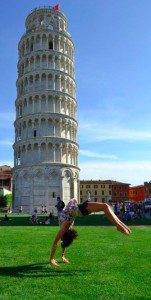 a woman doing a yoga pose in front of a leaning tower with Leaning Tower of Pisa in the background