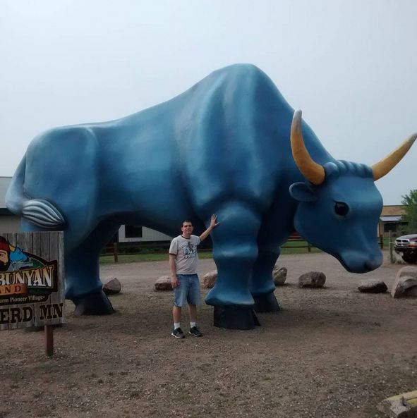 a man standing in front of a statue of a bull