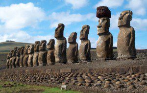 a row of stone statues with Easter Island in the background