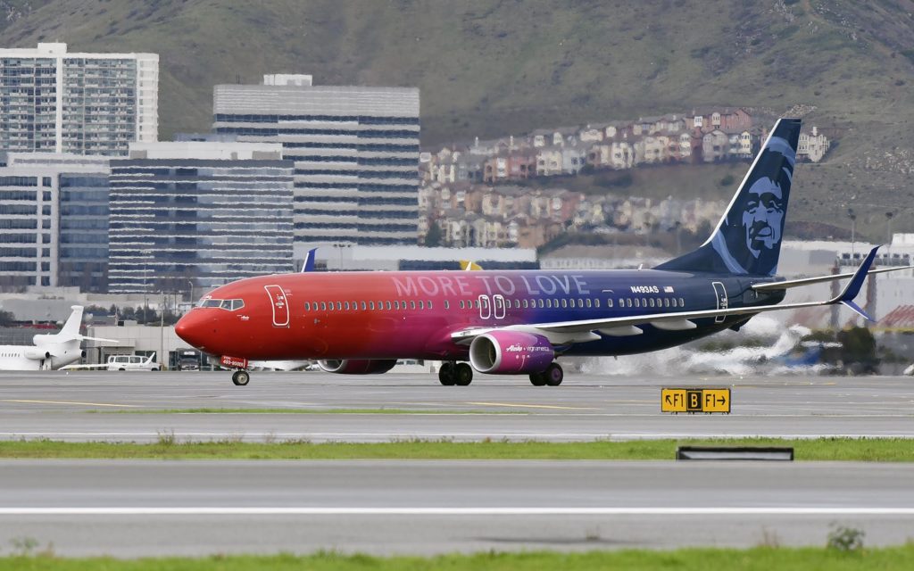In this photo released by Alaska Airlines, A specially painted, co-branded Alaska Airlines and Virgin America 737-900ER aircraft, painted in shimmering red, purple and blue and featuring the slogan “More to love,” lands at San Francisco International Airport on December 14, 2016 in San Francisco, CA. The newly painted aircraft is part of the merger celebration of Alaska Airlines and Virgin America. (Photo by Alaska Airlines, Bob Riha, Jr.)