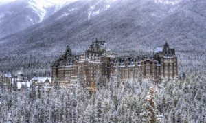 a large building surrounded by trees in front of mountains