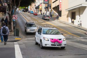 a white car with a pink mustache on the front of it