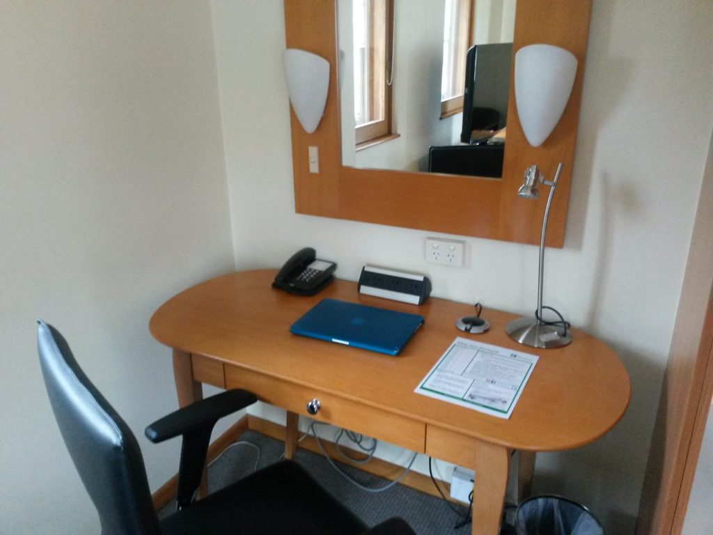 a desk with a laptop and a mirror