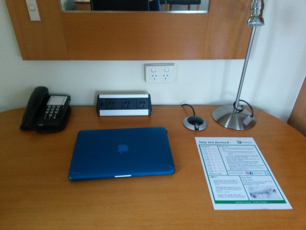 a desk with a laptop and telephone and a phone