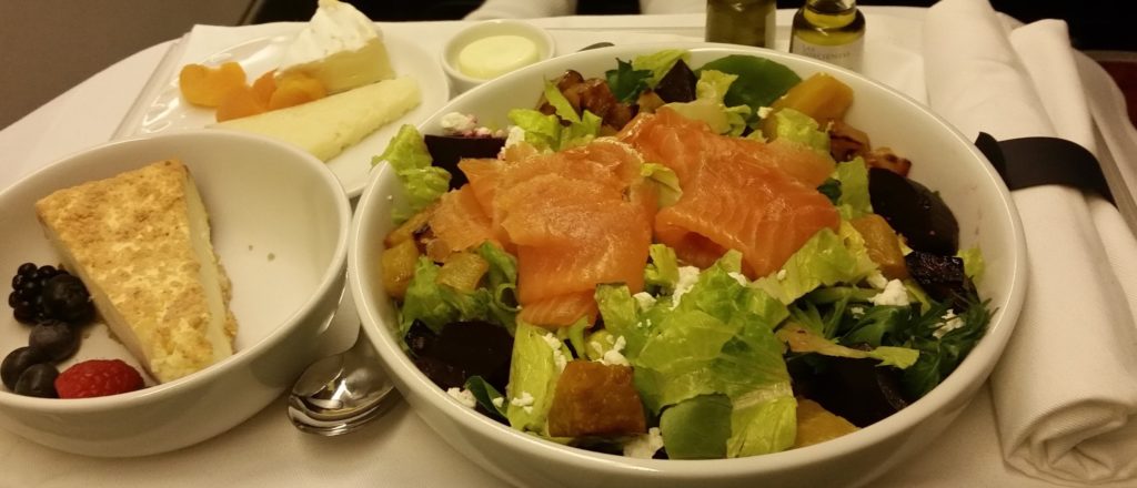 a bowl of salad with salmon and other food