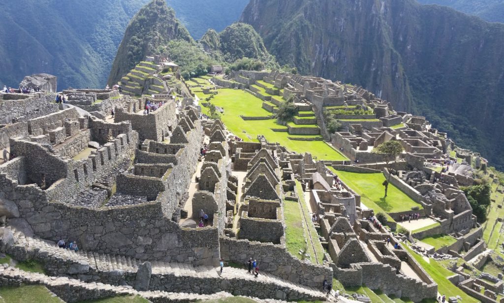 stone buildings on a hillside with Machu Picchu in the background