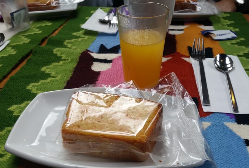 a plate with food on it and a glass of juice on a colorful tablecloth