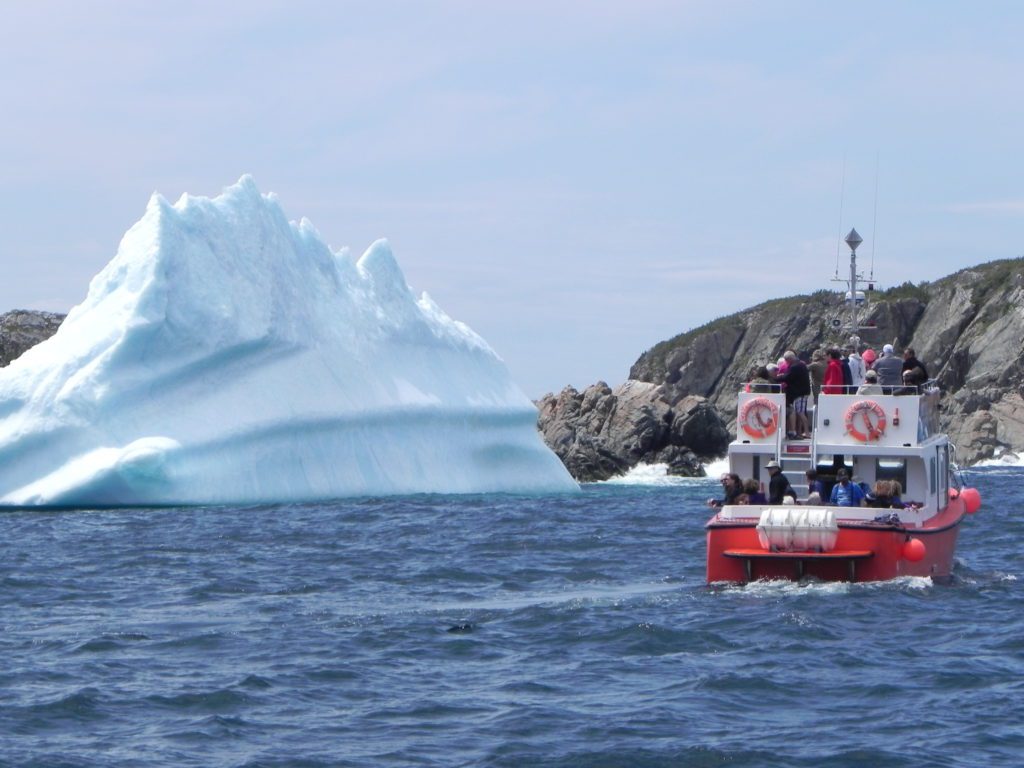 a boat on the water with a large iceberg in the background