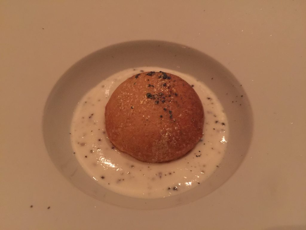 a round brown object with black specks on top of a white sauce