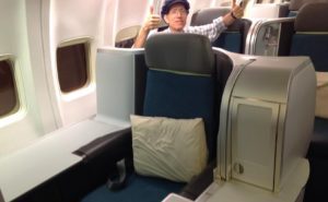 a man sitting in an airplane with his thumbs up