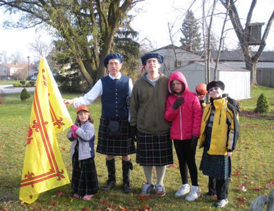 a group of people standing in a yard with a flag