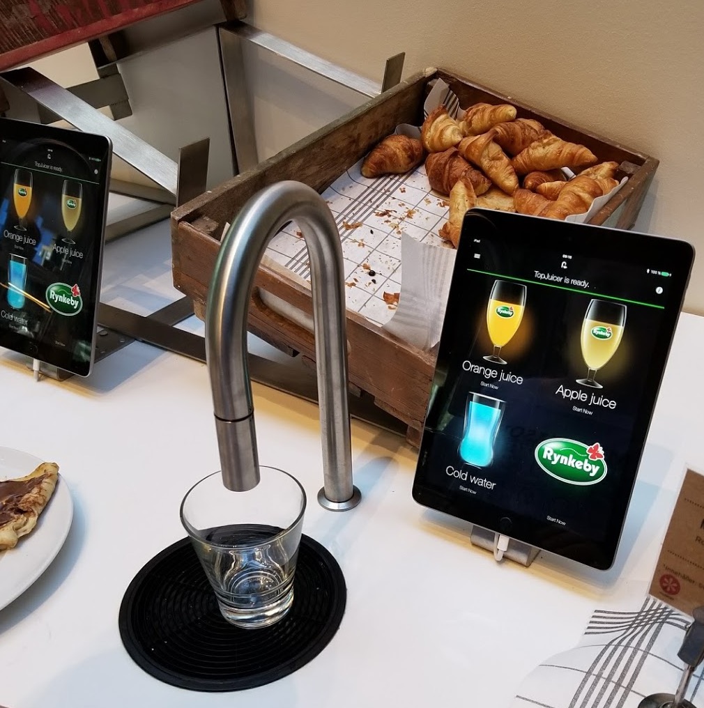 a tablet on a table with a glass and a tray of pastries