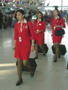 a group of women in red uniforms walking with luggage