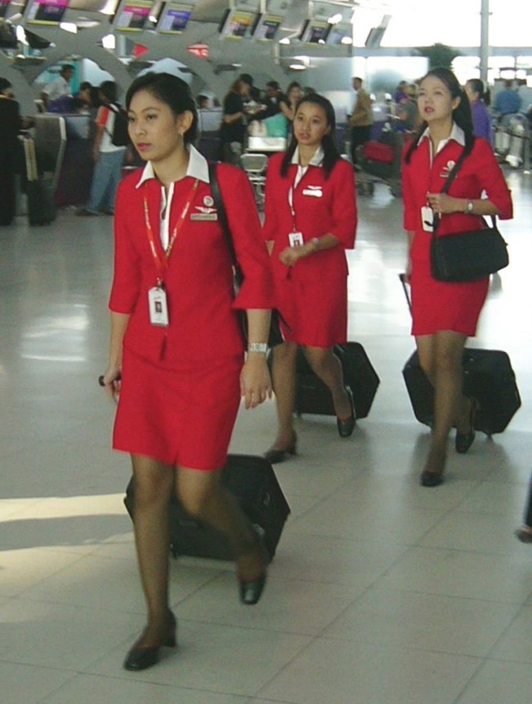 a group of women in red uniforms walking with luggage