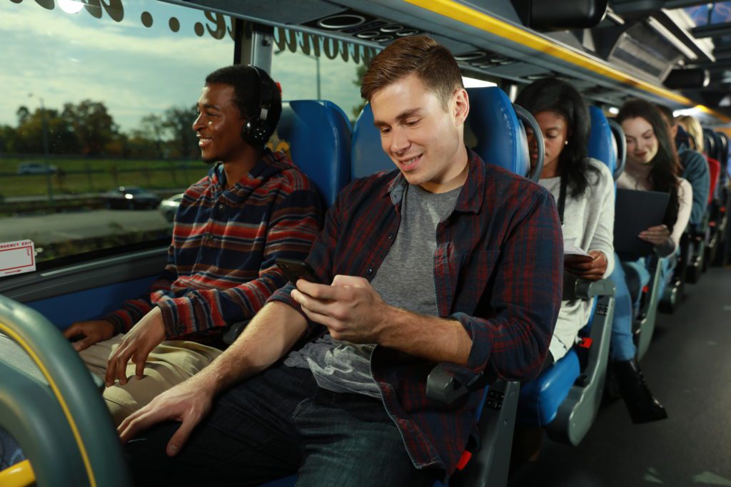 a group of people sitting on a bus looking at a phone
