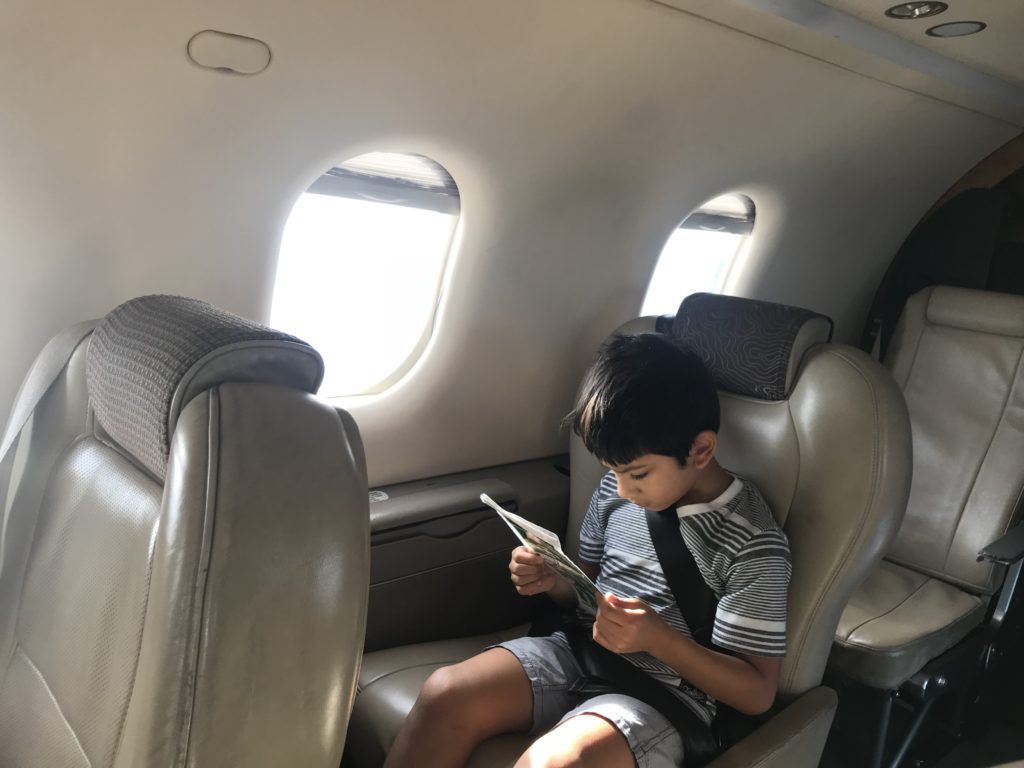 a boy sitting in a plane reading a book