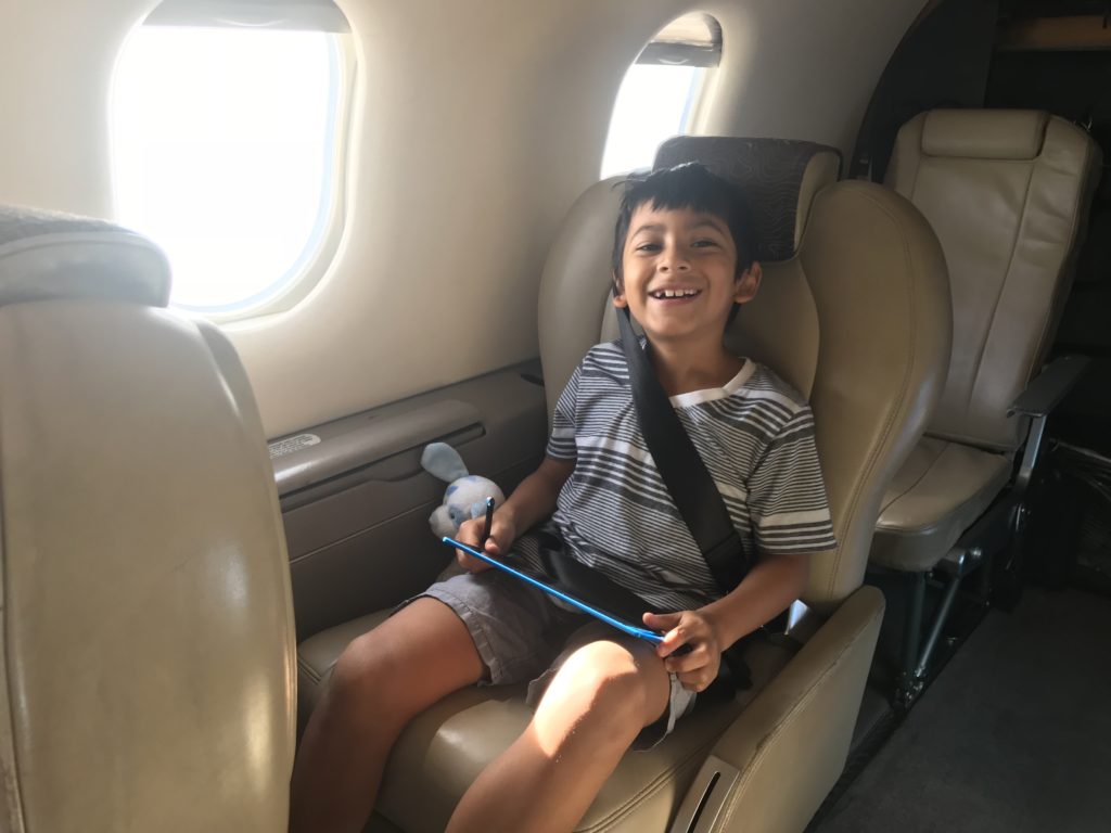 a boy sitting in a plane with a tablet