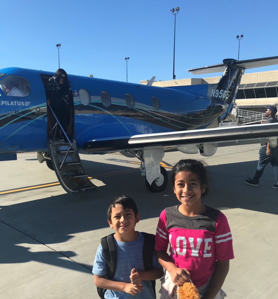 a boy and girl standing in front of a plane