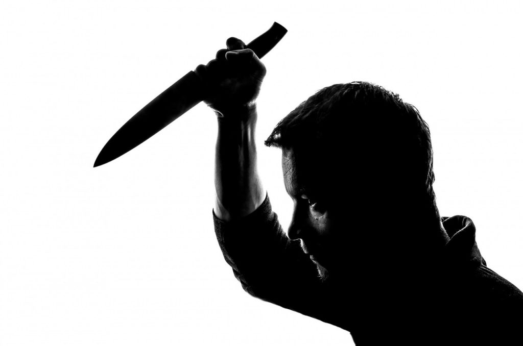 a silhouette of a man holding a knife