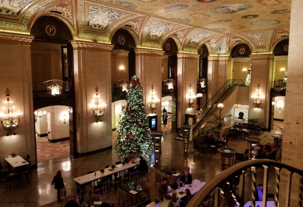 a large room with a decorated tree and people sitting at tables