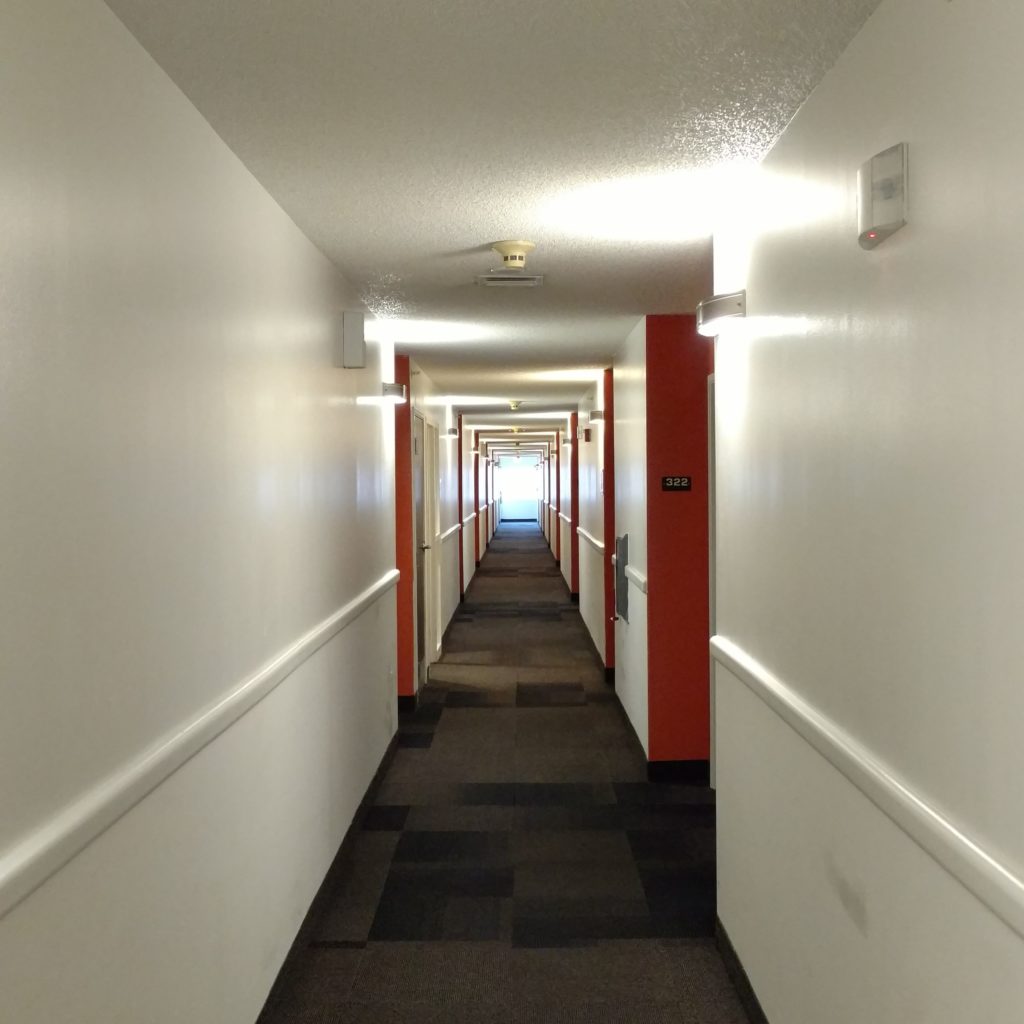 a long hallway with white walls and red doors
