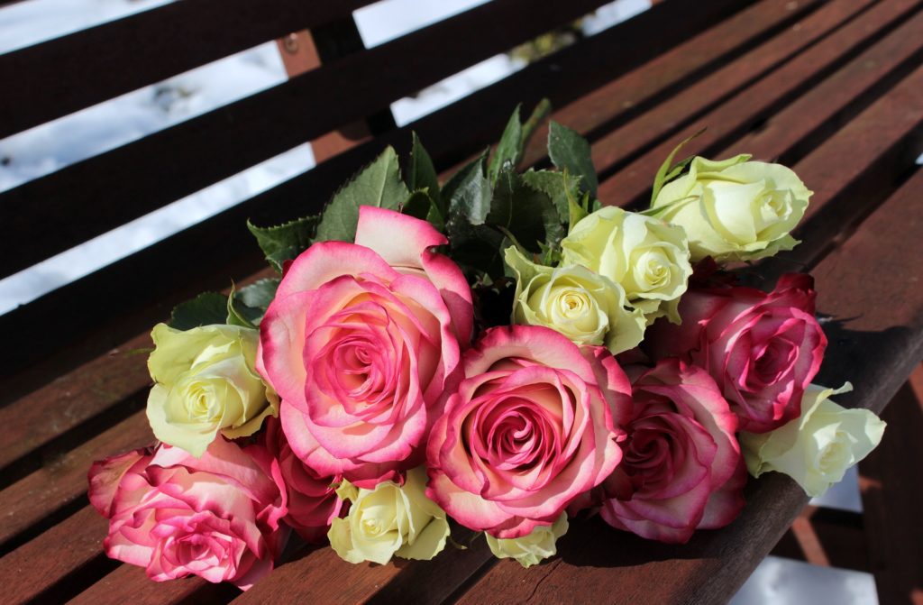 a bouquet of roses on a bench