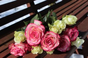 a bouquet of pink and white roses on a bench