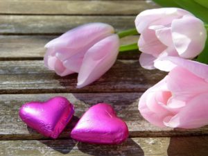 pink tulips next to chocolate hearts