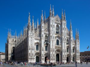 a large stone building with many people around it with Milan Cathedral in the background