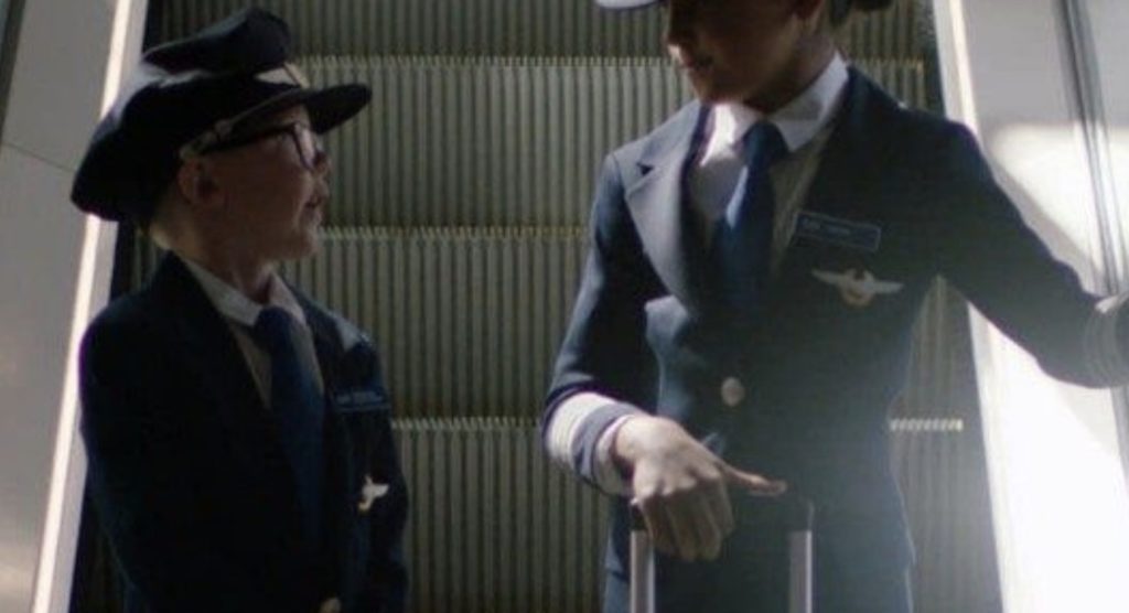 a boy in uniform holding a suitcase and pointing at another boy