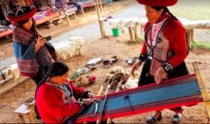 a woman in red and black clothes weaving a loom