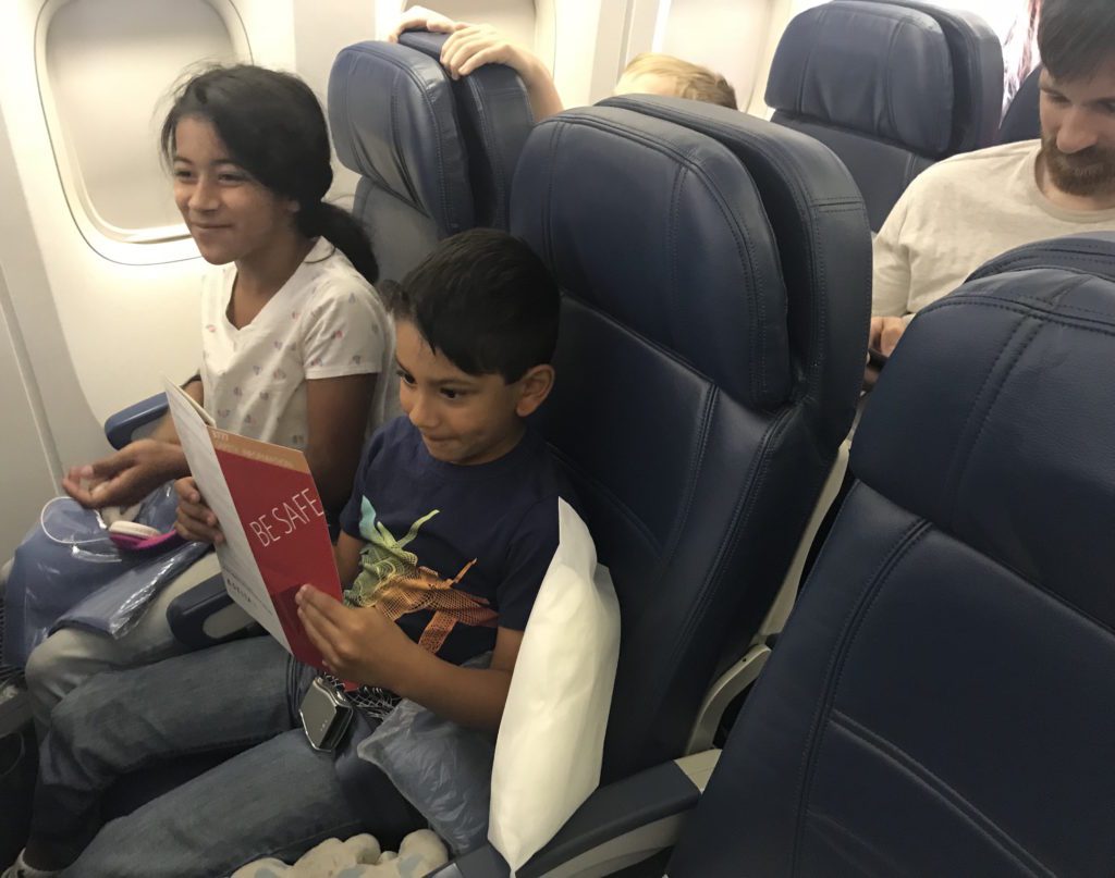 a group of children sitting in chairs on an airplane