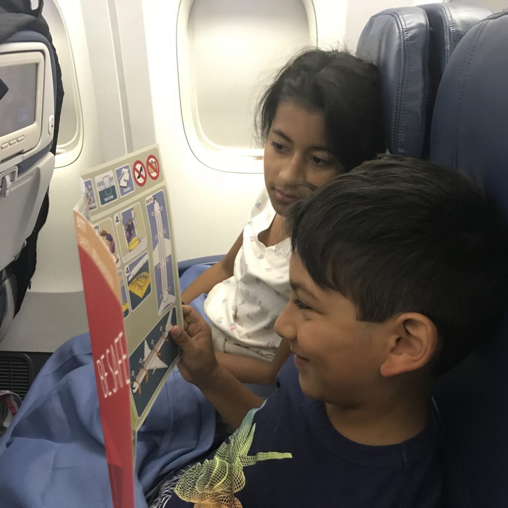 a boy and girl reading a book on an airplane