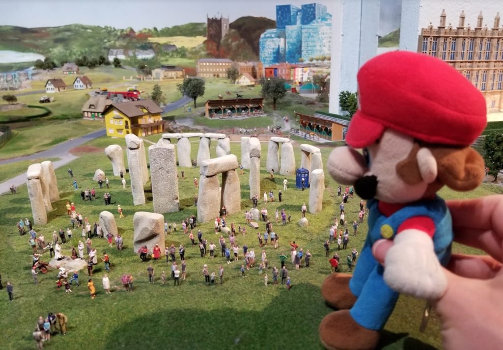 a toy animal and a group of people around a stone monument