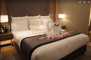 a bed with a couple swans made of towels and petals