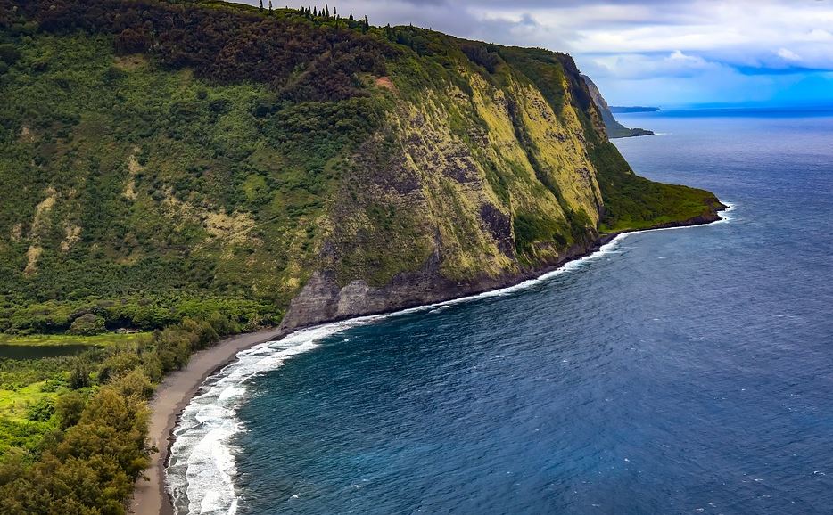 a beach with a rocky cliff and a body of water