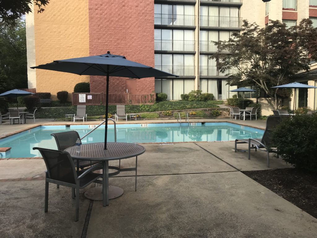 a pool with chairs and umbrellas by a building