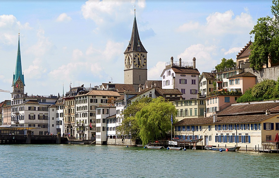 a city with a clock tower and buildings along the water