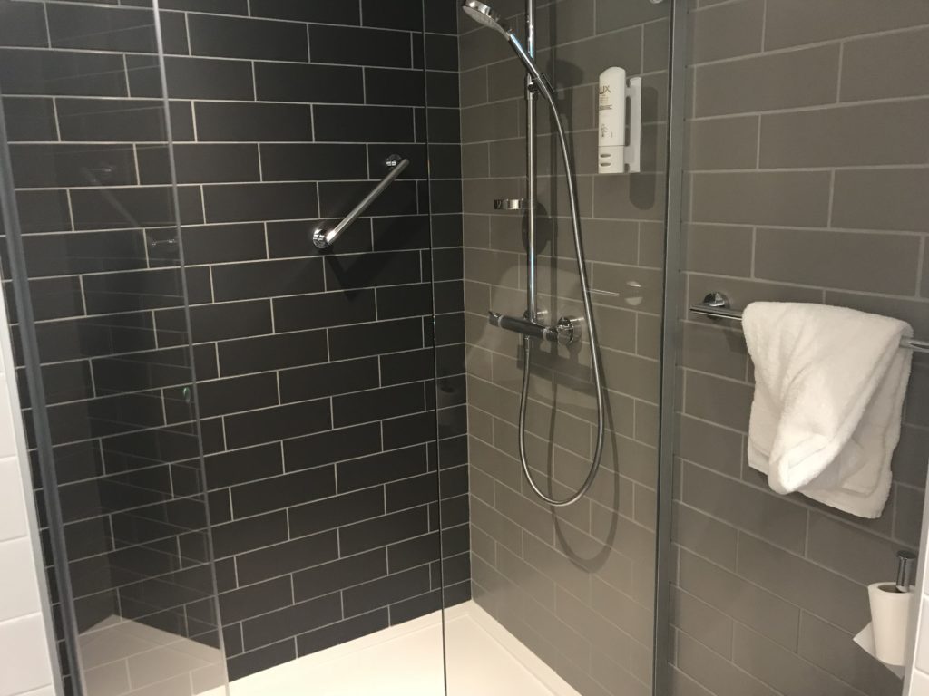 a shower with a grey tile wall