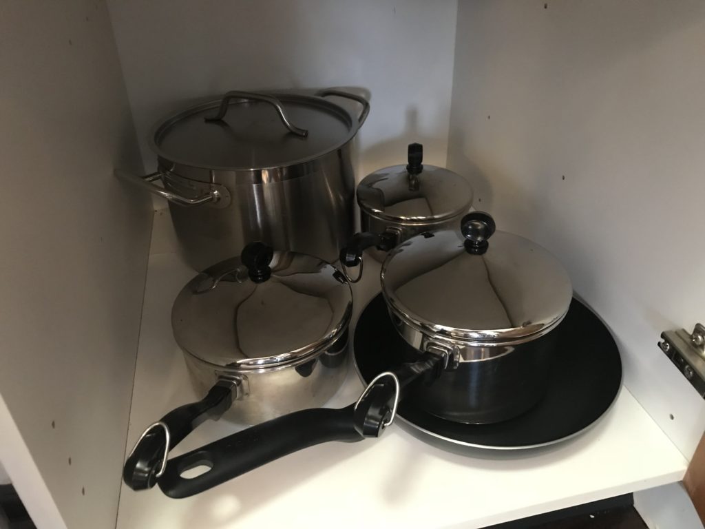 a group of pots and pans in a corner of a cabinet