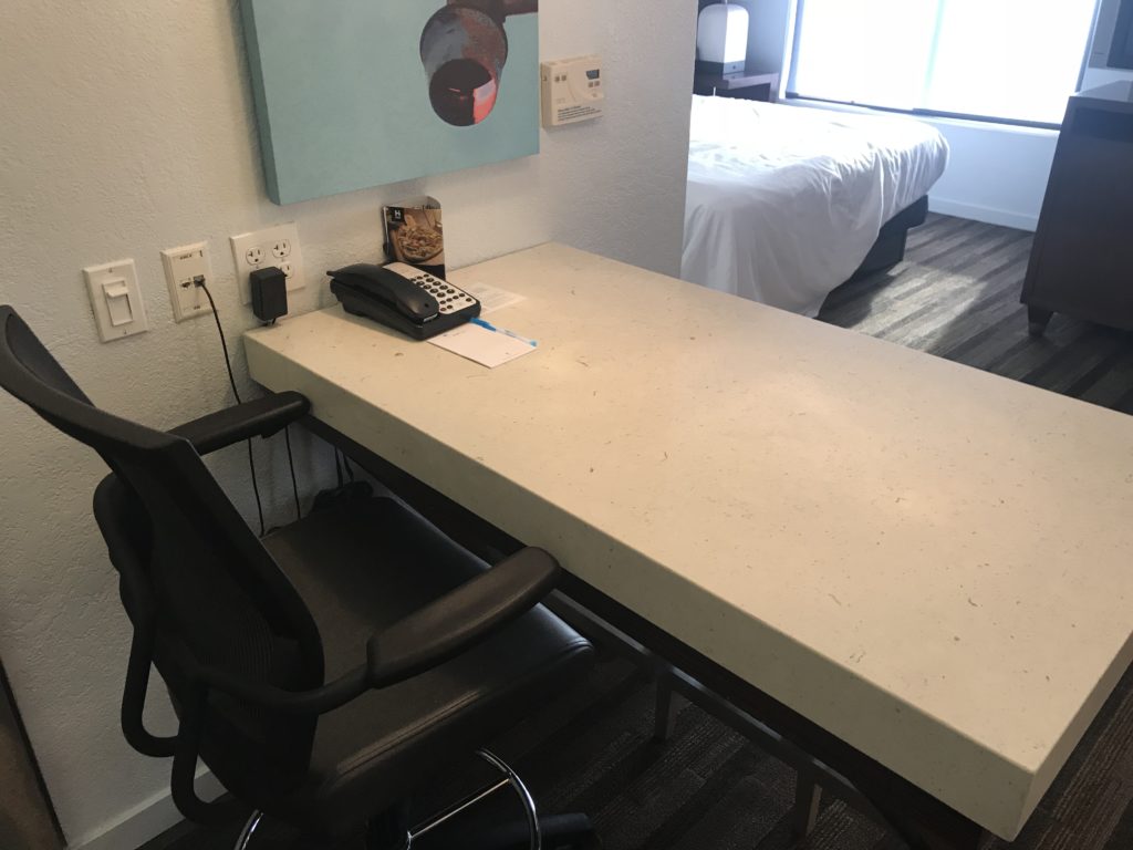 a desk with a telephone and chair in a hotel room