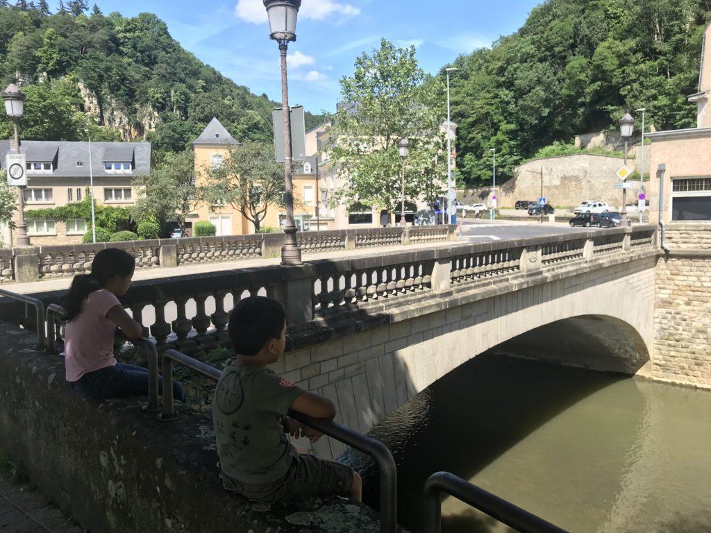 two children sitting on a bridge over a river