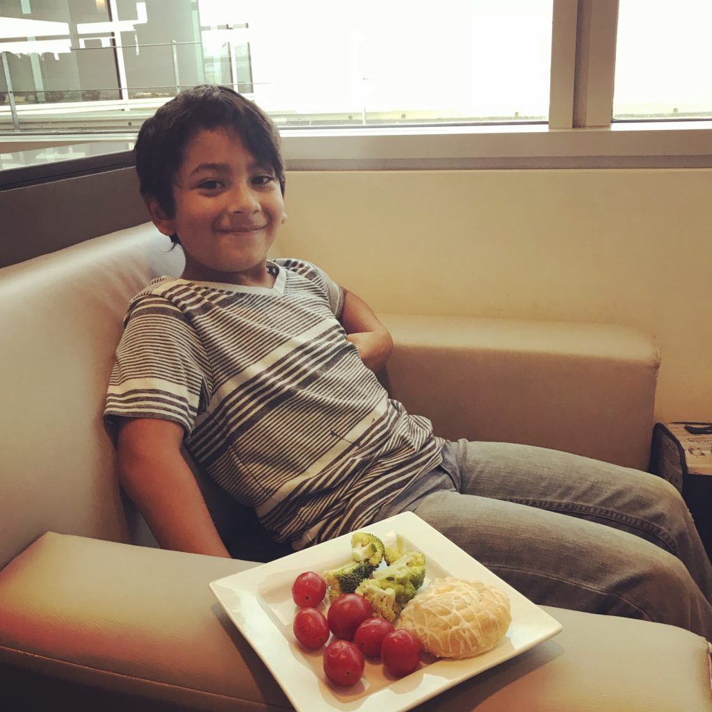 a boy sitting in a chair with a plate of food