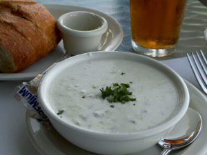 a bowl of soup with a glass of beer and bread