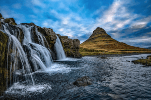 a waterfall next to a mountain