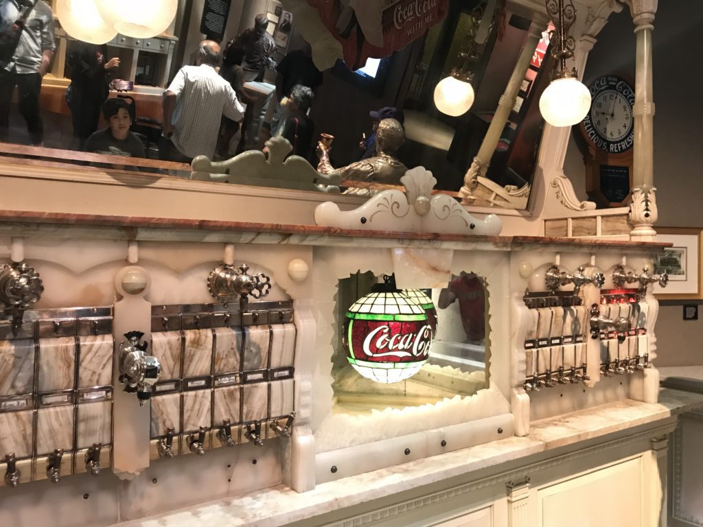 a counter with a mirror and a soda dispenser