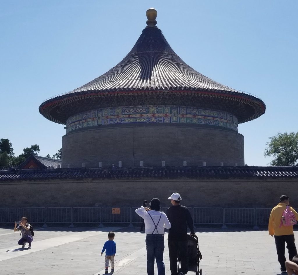 a group of people standing in front of a circular building with Temple of Heaven in the background